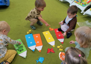 Dzieci bawią się sensorycznymi kredkami na dywanie.