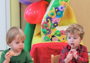 Leon i Gabriel siedzą przy stole i częstują się urodzinowymi smakołykami.