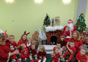Grupa dzieci w towarzystwie opiekunek i Świętego Mikołaja.