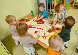 Dzieci tworzą farbami jesienny pejzaż na kartonie.