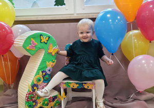 Uśmiechnięta Alinka siedzi na urodzinowym krześle.