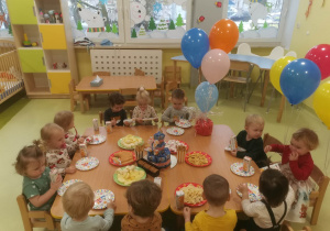 Dzieci siedzą przy stoliku i świętują urodziny koleżanek.