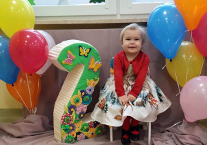 Uśmiechnięta Julka siedzi na urodzinowym krześle.