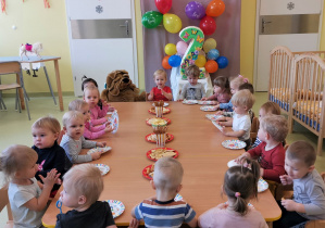 Dzieci siedzą przy stolikach przy urodzinowym poczęstunku.