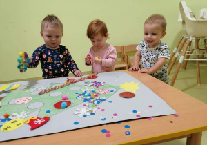 Filip, Jagoda i Staś ozdabiają choinkę na brystolu.