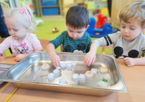 Gabriel, Dominik i Amelka bawią się lodowymi kostkami.