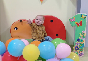 Józio wśród balonów z urodzinową cyfrą.