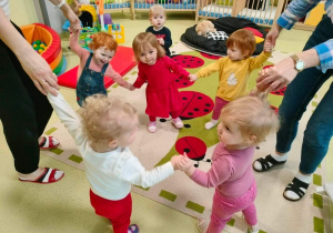 Dzieci tańczą razem w kółku i trzymają się za ręce.