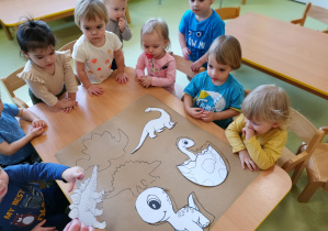 Dzieci dopasowują kształt dinozaurów do ich konturów.