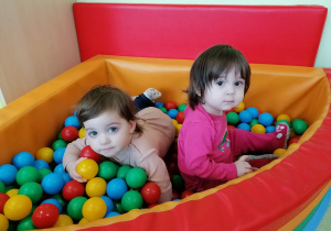 Hania i Natalia bawią się wspólnie w basenie z kolorowymi piłeczkami.