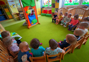 Dzieci siedzą na krzesełkach i oglądają teatrzyk o Czerwonym Kapturku.