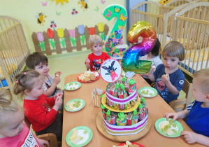 Olaf siedzi z dziećmi przy stole podczas urodzinowego poczęstunku.