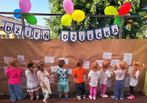 Dzieci kolorują kredkami obrazki na tarasie.