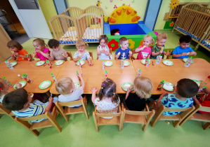 Dzieci siedzą przy stolikach podczas poczęstunku z okazji Dnia Dziecka.