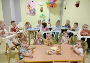 Wszystkie dzieci siedzą przy poczęstunku urodzinowym i wspólnie świętują.