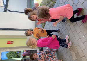 Dzieci tańczą na dworze w rytm dziecięcych utworów.