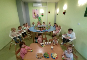 Dzieci siedzą wspólnie przy urodzinowym poczęstunku.