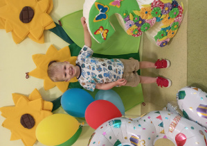 Jasio pozuje do urodzinowego zdjęcia przy cyferce trzy i kolorowych balonach.