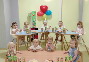 Dzieci wspólnie siedzą przy urodzinowym poczęstunku.