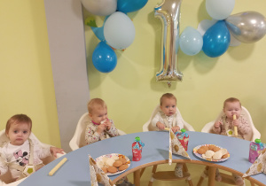 Dzieci siedzą i jedzą urodzinowy poczęstunek Jakuba.