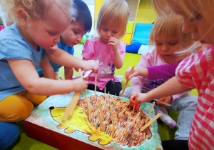 Dzieci tworzą jeża wykorzystując drewniane patyczki.