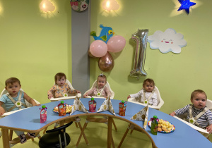 Dzieci siedzą przy stole i jedzą słodki poczęstunek