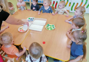 Dzieci siedzą przy stole i wspólnie wykonują eksperyment pt. " Tęcza na mleku"..