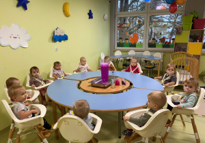 Dzieci siedzą przy stole i oglądają kolorowy wulkan.
