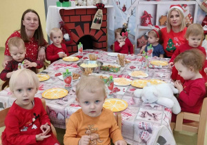 Dzieci siedzą przy wspólnym poczęstunku Mikołajkowym.