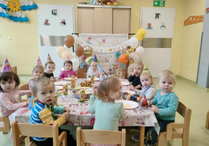 Dzieci wspólnie siedzą przy urodzinowym poczęstunku.