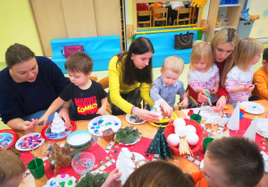 Dzieci wspólnie z rodzicami wykonują ozdoby świąteczne.