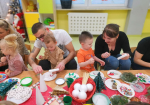 Dzieci wspólnie z rodzicami wykonują ozdoby świąteczne.