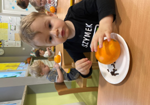 Szymon zdobi pomarańczę goździkami.