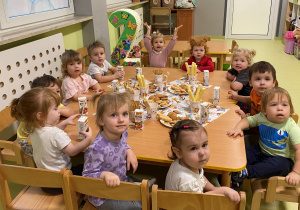Dzieci siedzą przy stoliku i jedzą pyszne słodkości.