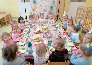 Wszystkie dzieci siedzą przy urodzinowym poczęstunku.