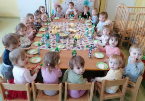 Dzieci siedzą przy stole przy urodzinowym poczęstunku.