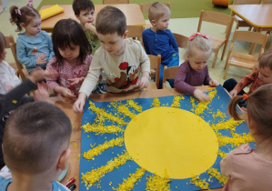 Dzieci wspólnie robią marcowe słoneczko.