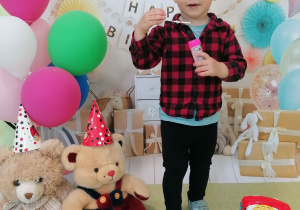 Ignacy z pluszowymi misiami i balonikami pozuje do urodzinowego zdjęcia.
