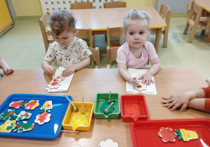 Zosia i Kinga malują farbami kwiatki dla mamy.