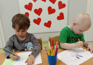 Mikołaj i Dominik kolorują kartkę na kolorowo, aby przygotować laurki.