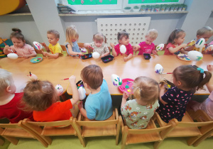 Dzieci malują farbami świąteczne jajka.