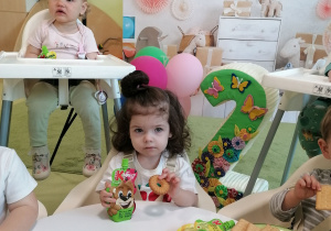 Hania siedzi przy stoliku i je ciasteczko.