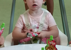 Hania siedzi przy stole i częstuje się ciastkiem.