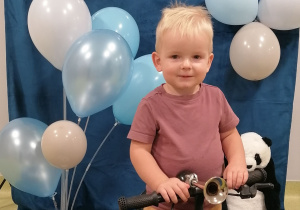 Mateusz siedzi na rowerze i pozuje do zdjęcia z okazji Dnia Chłopca.