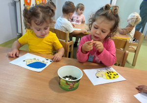 Roksana i Julia wyklejają jeżyki przy pomocy pestek dyni.