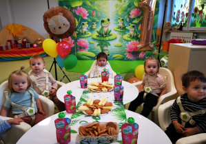 Tadej z dziećmi siedzi przy stoliku podczas urodzinowego poczęstunku.