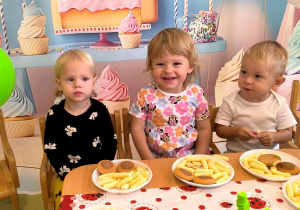 Antosia, Pola i Staś siedzą przy stole i jedzą słodki poczęstunek.