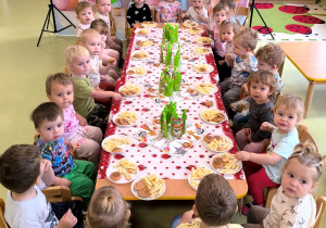 Wszystkie dzieci siedzą przy stole i jedzą słodki poczęstunek przygotowany przez rodziców Antosi.