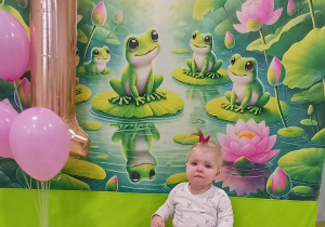 Zuzia pozuje do zdjęcia na urodzinowym tle.