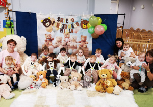 Dzieci i opiekunki z grupy Żabki pozują do wspólnego pamiątkowego zdjęcia z pluszowymi misiami.